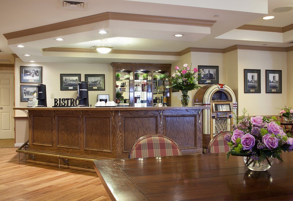 A welcoming hotel lobby featuring a wooden reception desk, floral arrangements, and cozy seating.
