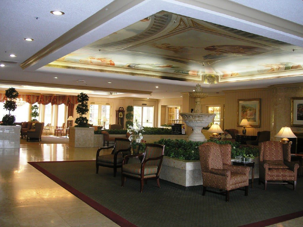A spacious hotel lobby with elegant furniture and a decorative ceiling.