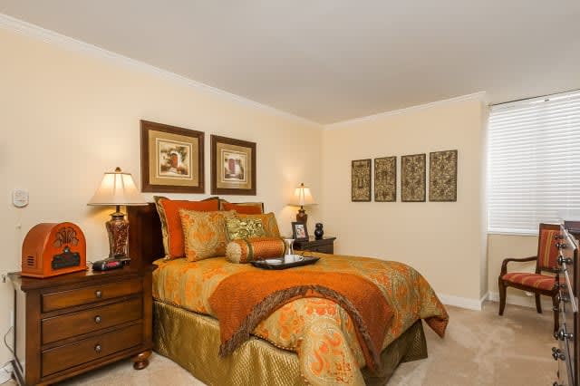 A cozy bedroom with warm-toned bedding and art on the walls.