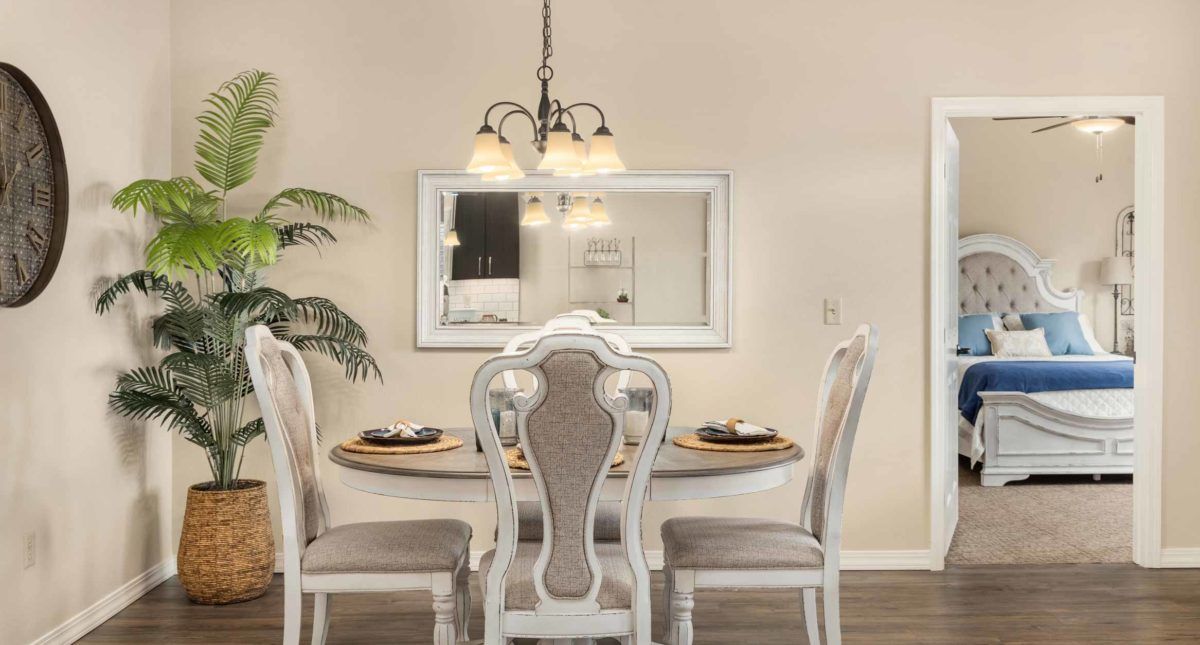 Elegant dining area with a round table, four chairs, and a stylish chandelier.