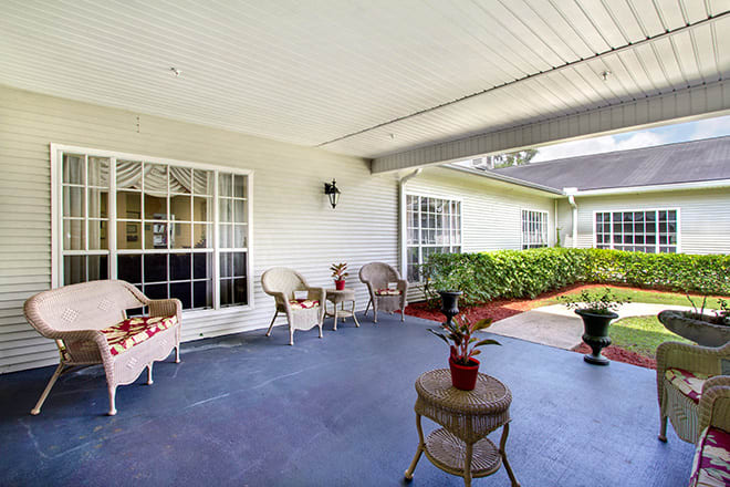 A cozy patio area with wicker furniture and potted plants under a covered space.
