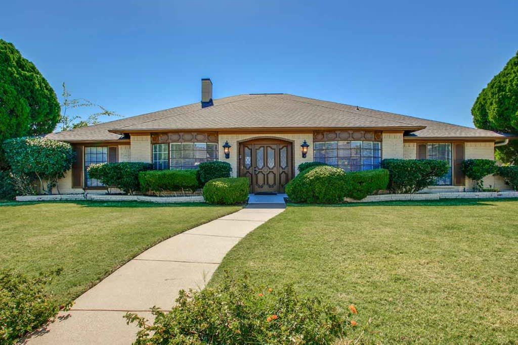 A suburban house with a well-maintained lawn and a clear blue sky.
