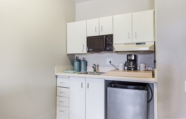 A compact kitchen with white cabinets, a microwave, and a coffee maker on the countertop.