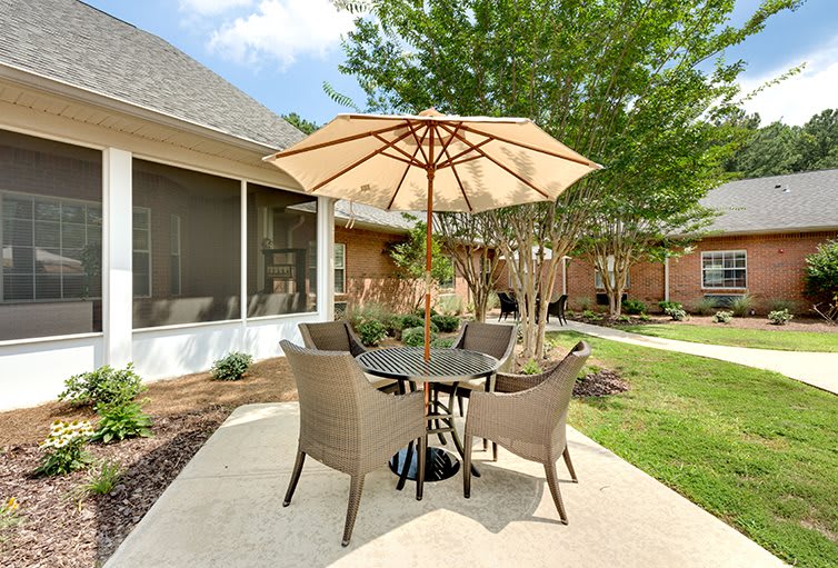 A cozy outdoor patio set with an umbrella, surrounded by a garden.