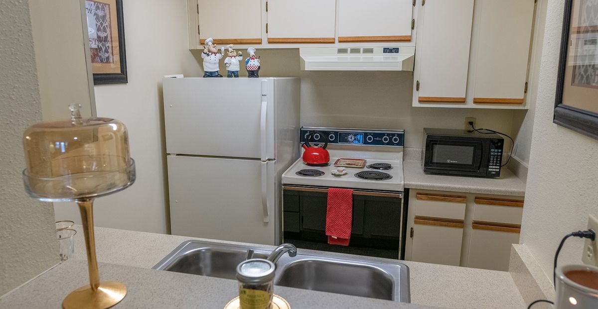 A compact kitchen with essential appliances including a refrigerator, stove, microwave, and sink.