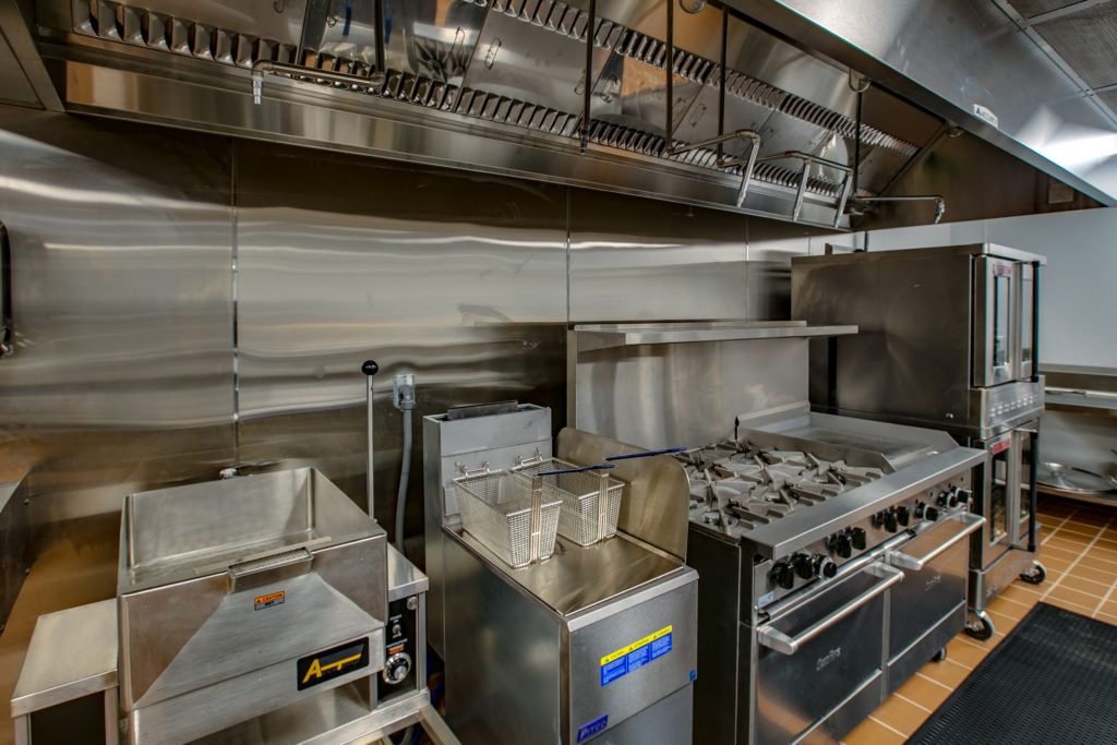 A well-equipped commercial kitchen featuring various stainless steel appliances and cooking equipment.