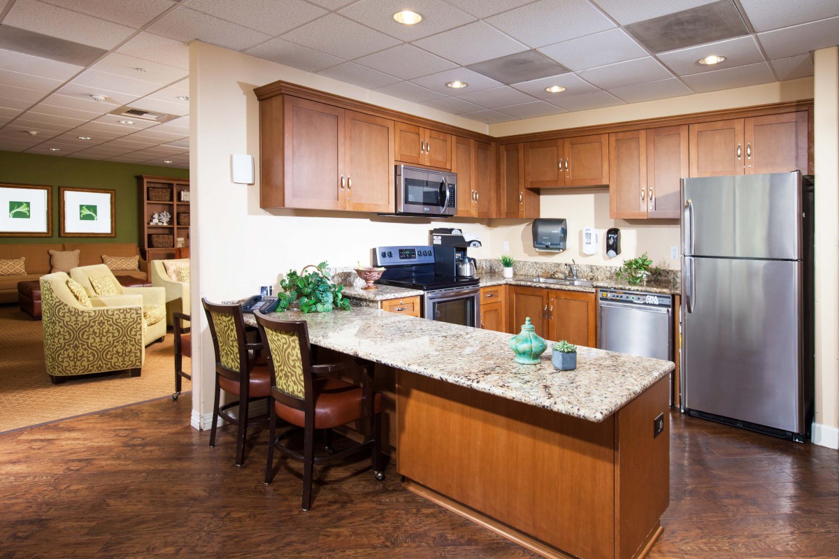 A modern kitchen with wooden cabinets, granite countertops, and stainless steel appliances.
