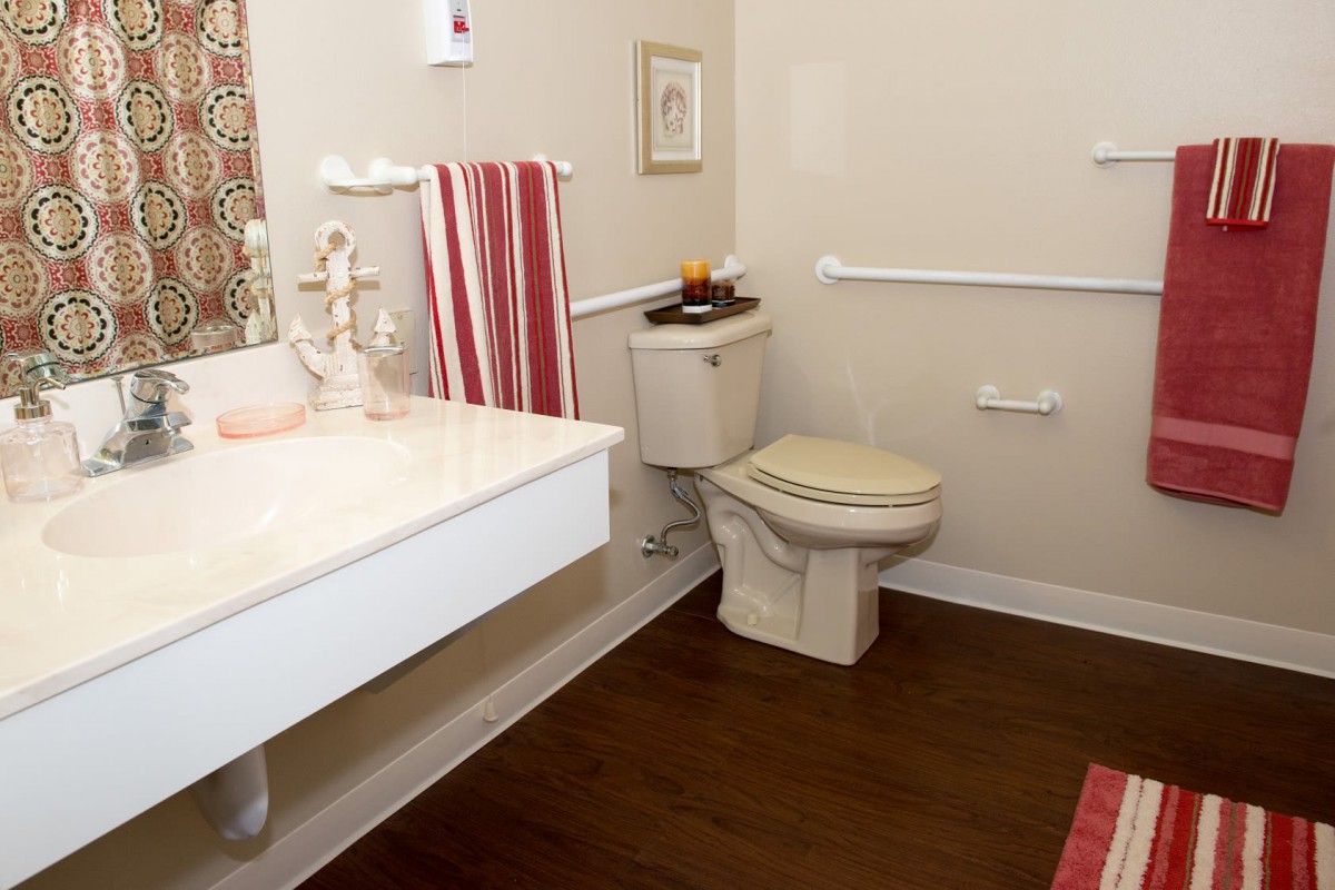 A well-organized bathroom featuring a toilet, sink, striped towels, and decorative elements on the wall.