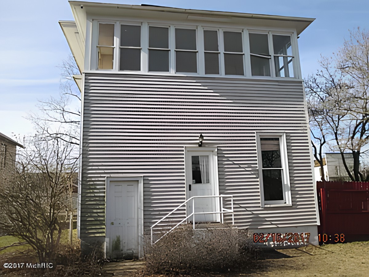 A two-story house with large windows and a small entrance porch.