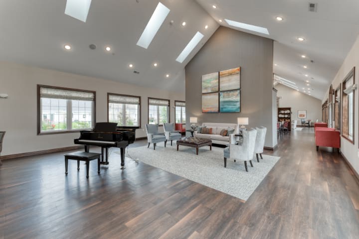 A spacious and modern living room featuring a grand piano, comfortable seating, skylights, and elegant decor.