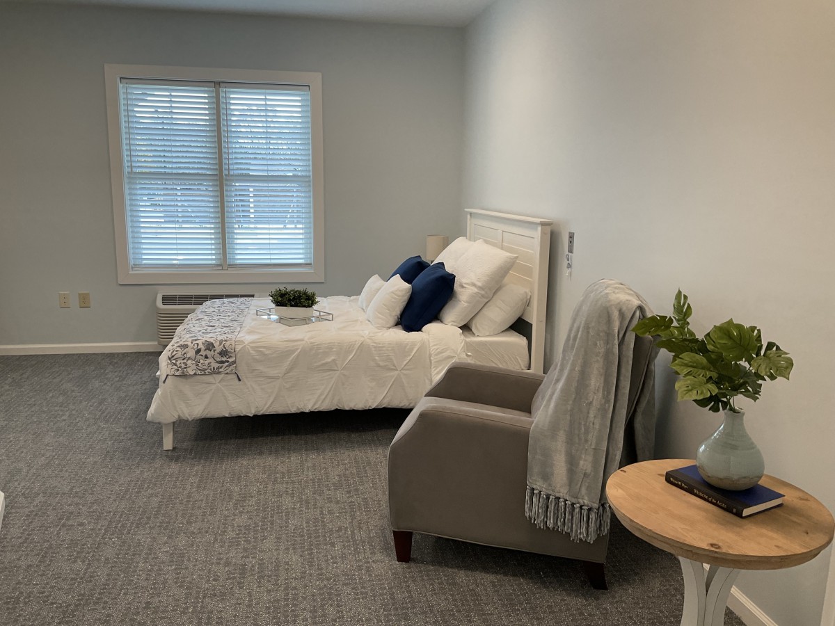 A minimalist bedroom with a cozy bed and a comfortable chair.