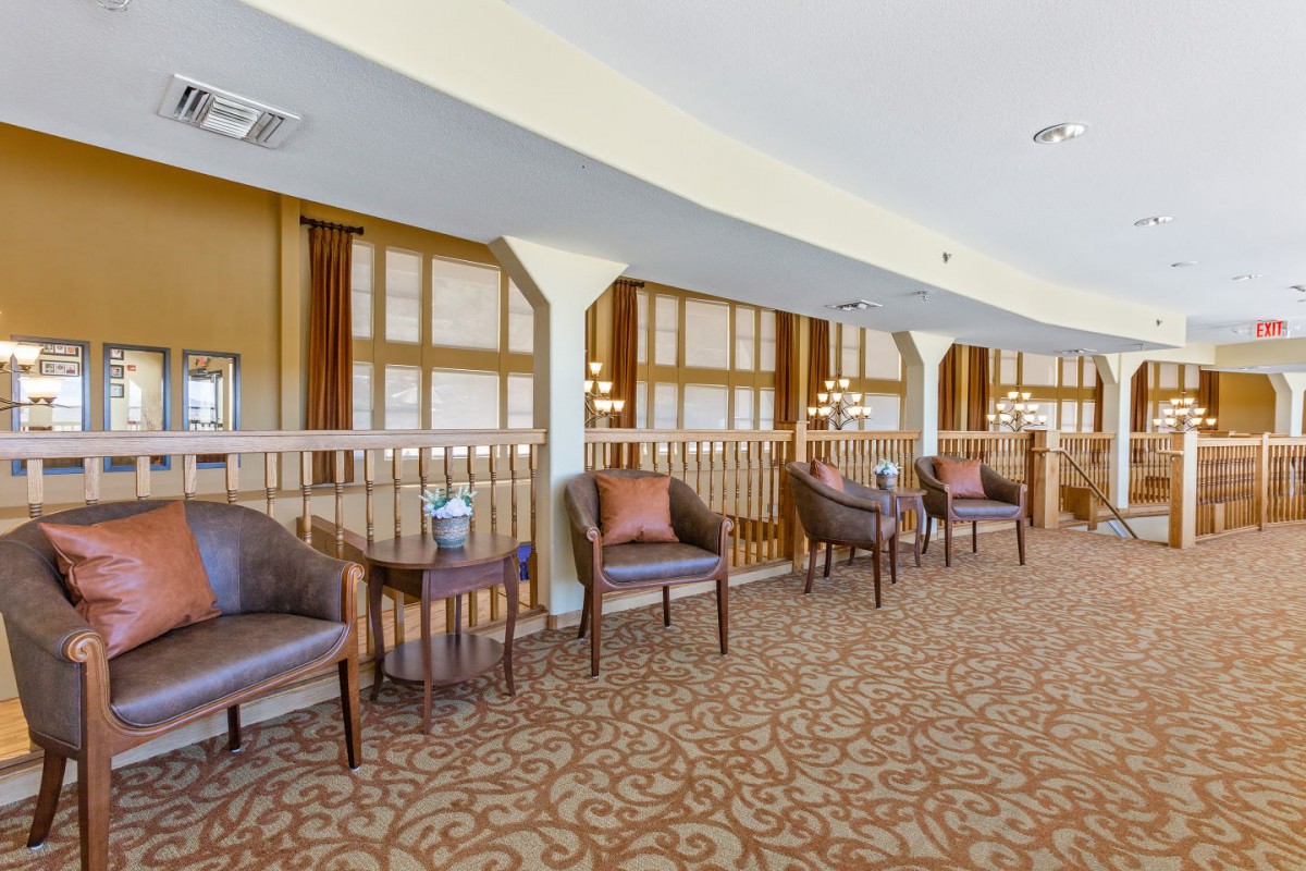 A cozy lobby seating area with chairs and tables arranged along a carpeted space.