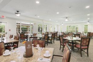 An elegant dining area with neatly arranged tables and chairs, illuminated by overhead lighting.