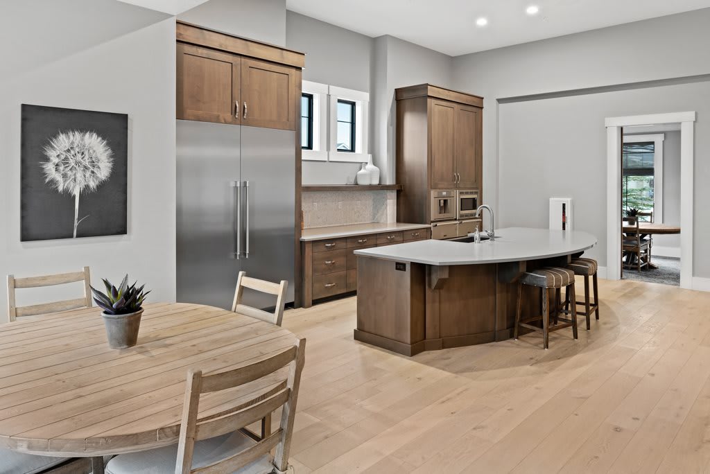 A modern kitchen featuring wood cabinets, a large island counter, and stainless steel appliances, seamlessly connected to a dining area.