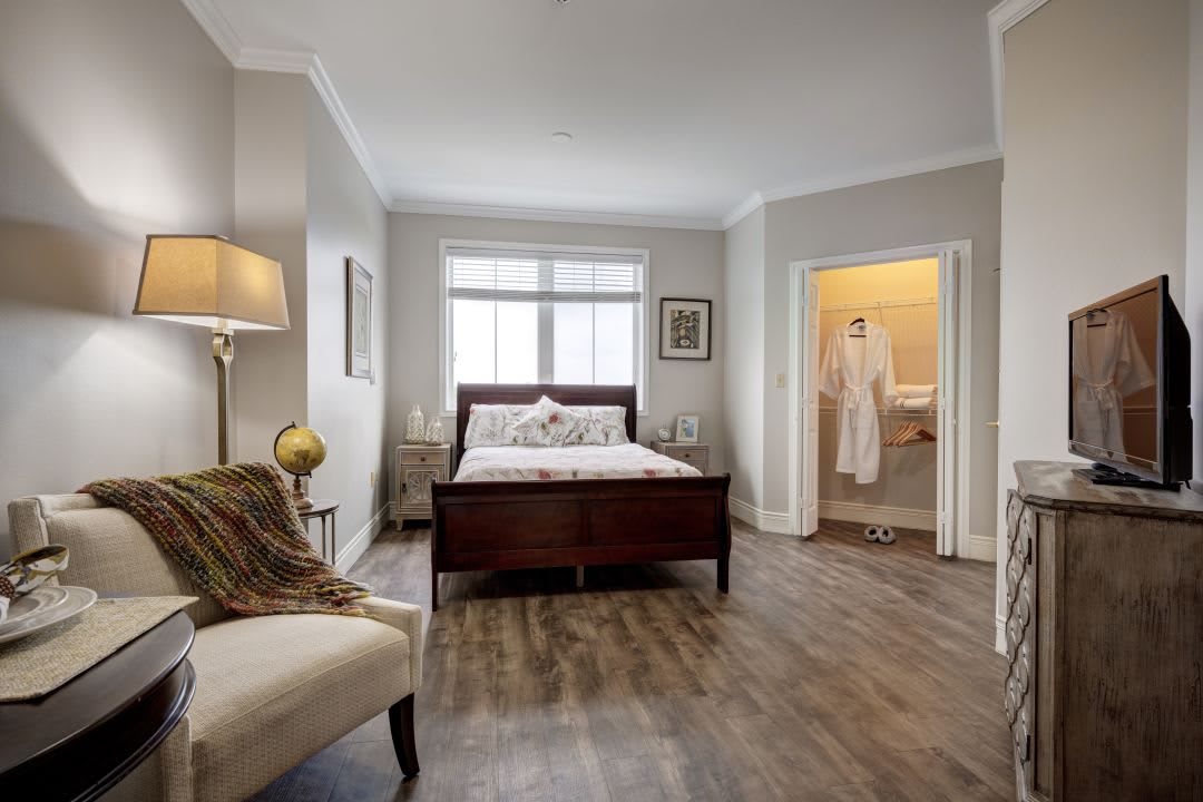 A modern bedroom interior with a cozy setup, featuring a bed, armchair, and decorative elements.