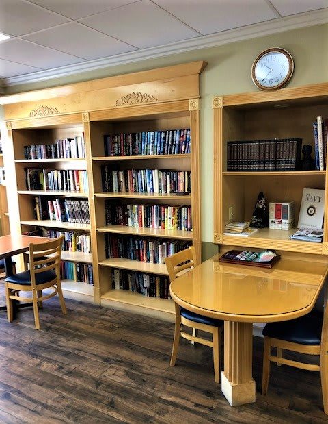 A cozy library reading area with bookshelves, tables, and chairs.