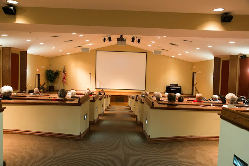 A spacious auditorium setup for presentations, featuring a large screen and arranged seating.