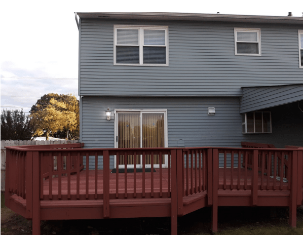 A two-story house with a spacious wooden deck in the backyard.