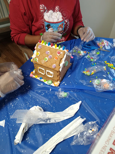 Individuals enjoying a fun and creative gingerbread house decorating session.