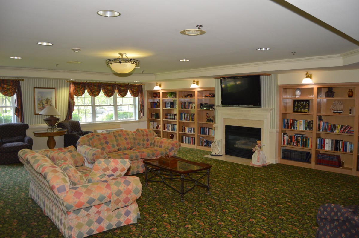 A cozy living room with a seating area, bookshelves, and a fireplace.