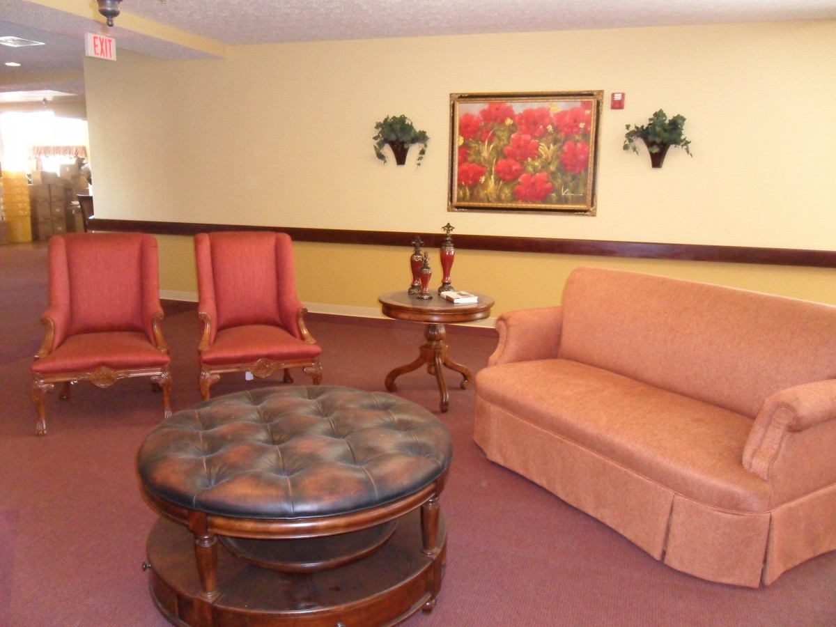 A cozy living room with a sofa, two chairs, and a round coffee table, accented by wall art and small decorative plants.