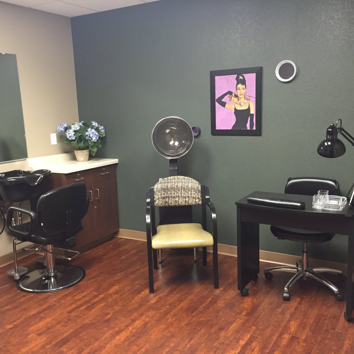 A cozy beauty salon interior with a styling chair, mirror, hair dryer, and nail station.