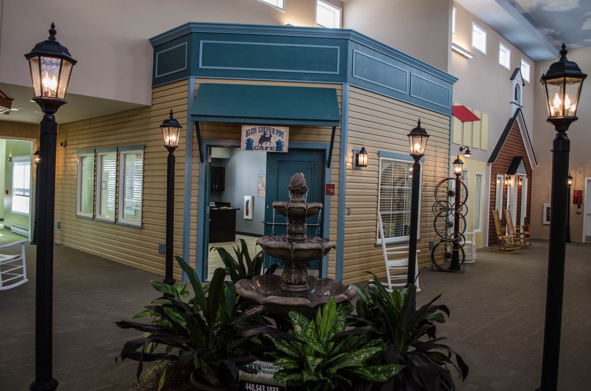 Indoor area with a decorative fountain and plants in front of a storefront.