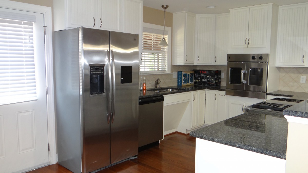 Modern kitchen with stainless steel appliances and white cabinets.