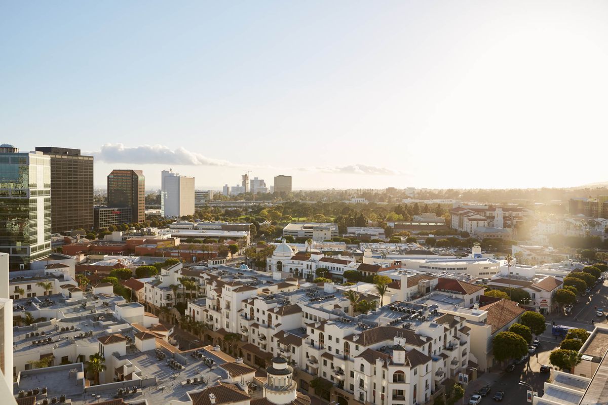 Aerial view of a cityscape at sunset with buildings and a clear skyline.