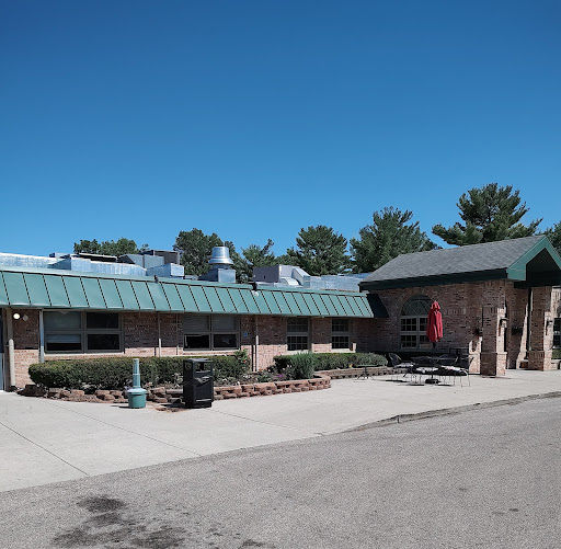 A view of a well-maintained building with a green roof and landscaped area under a clear blue sky.