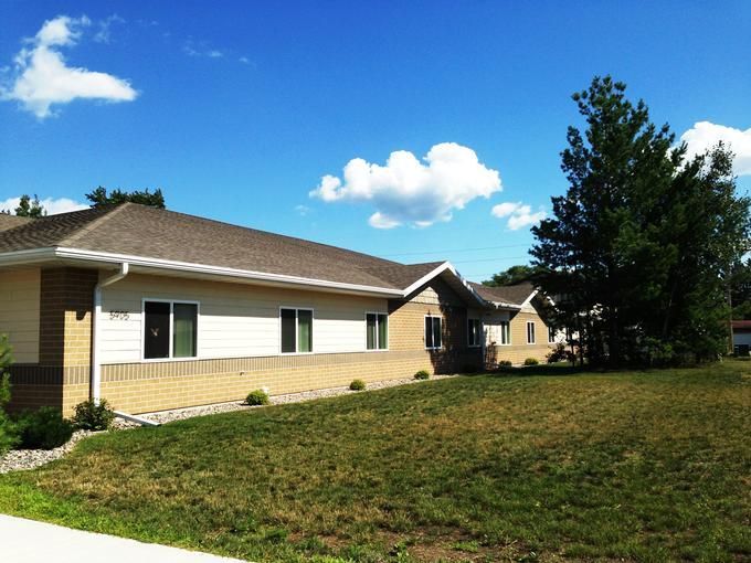 A single-story residential building with a grassy lawn under a clear blue sky.