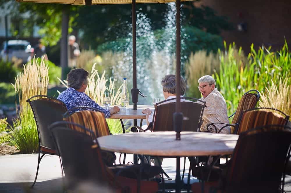 A group of people enjoying a conversation at an outdoor patio by a fountain.