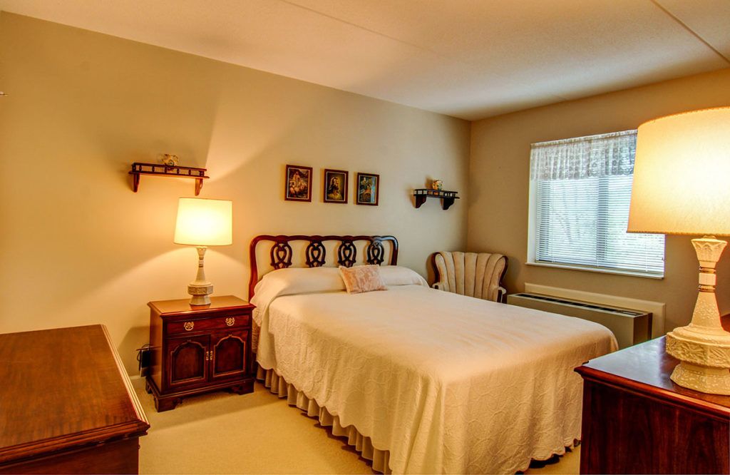 A cozy, traditionally decorated bedroom with a neatly made bed and soft lighting.