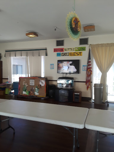 A view of a community room featuring tables and a television, decorated with colorful banners.
