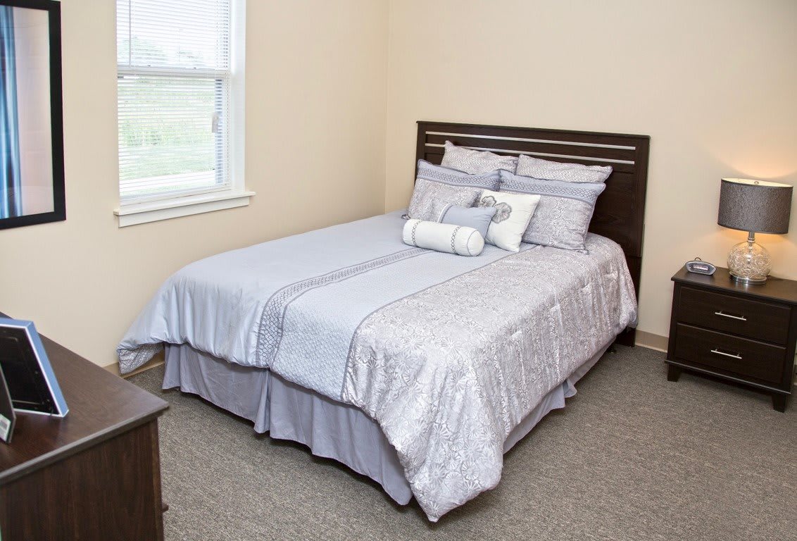 A neatly arranged double bed in a cozy bedroom with neutral-colored bedding and pillows.