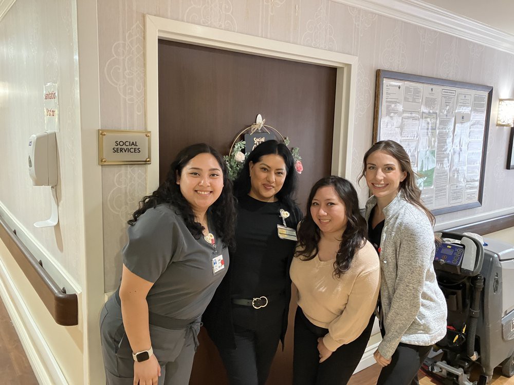 A group of four people posing and smiling indoors near a door.
