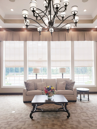 A beautifully designed living room featuring a comfortable sofa, elegant chandelier, and ample natural light from large windows.