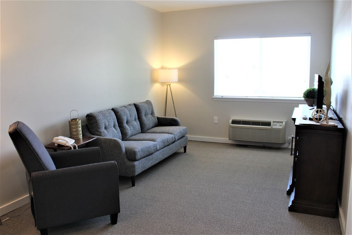 A simple and minimalistic living room with a sofa, lamp, and air conditioning unit.