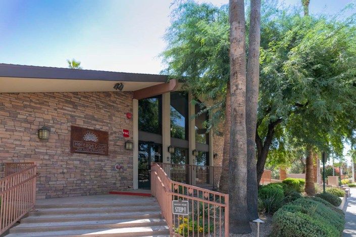 Entrance to a building with brick walls surrounded by trees and a palm tree.