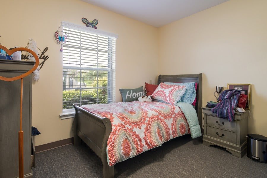 A cozy bedroom with a decorated bed and a window letting in natural light.