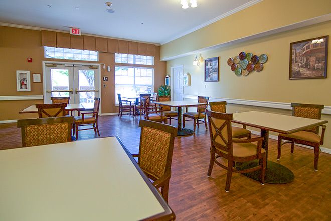 A cozy dining area with wooden floors and tables set for guests.