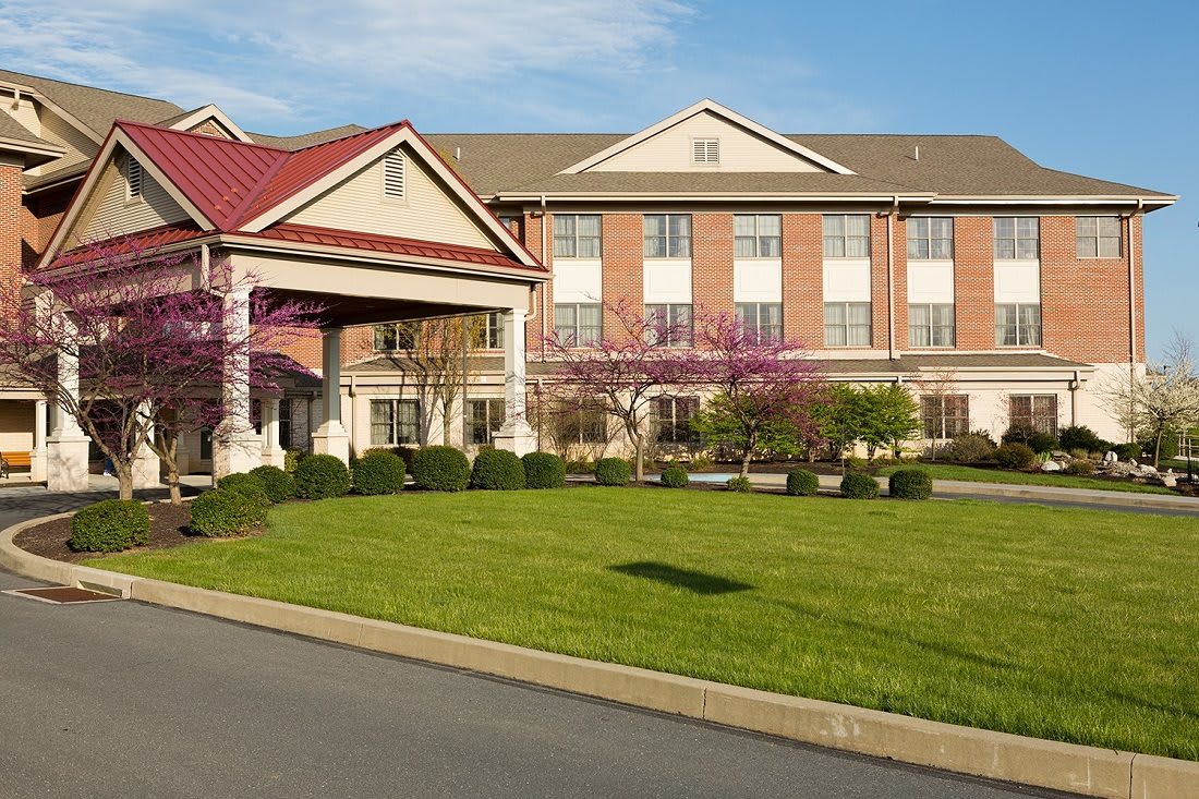 A modern hotel building with a well-maintained lawn and attractive landscaping at the entrance.