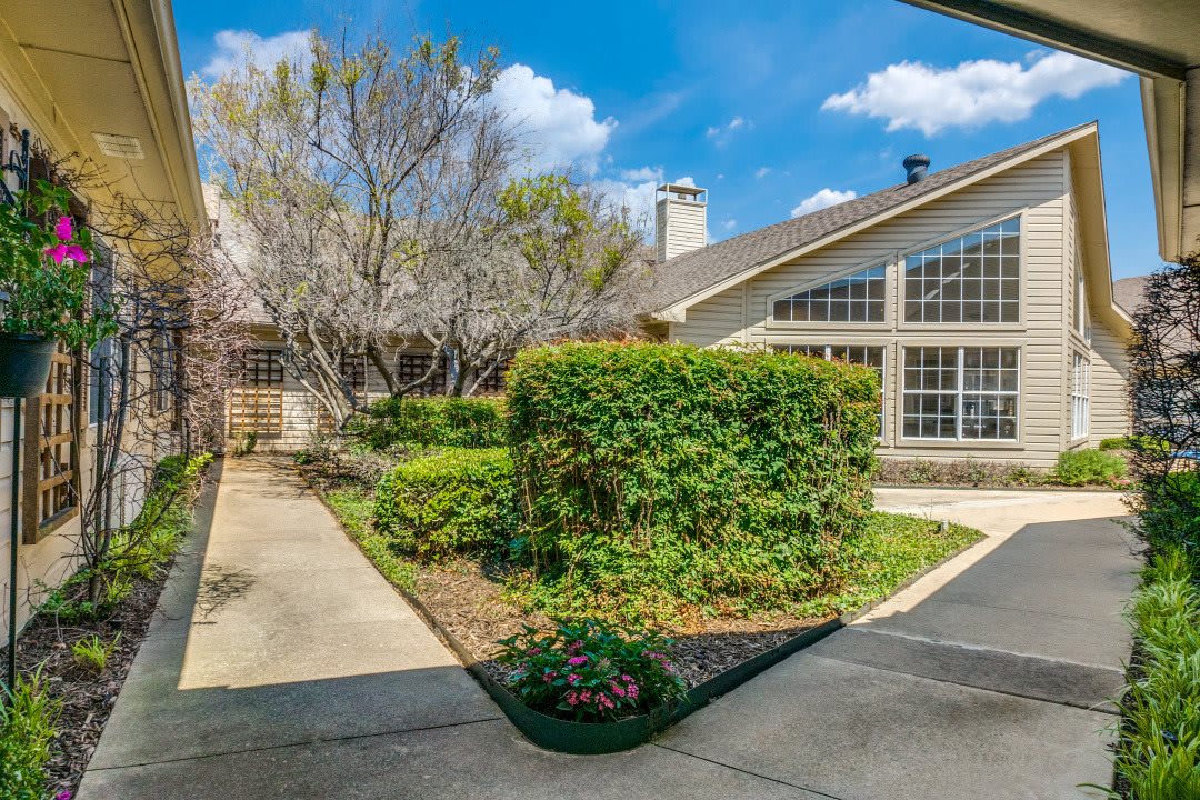 A beautiful house surrounded by a well-maintained garden with trees and bushes.