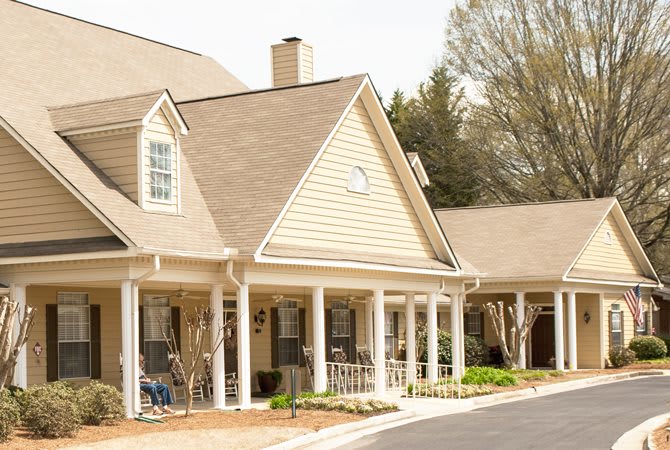 A suburban residential house with a spacious porch and surrounding trees.