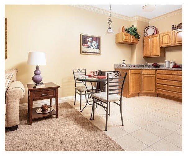 A cozy kitchen with a dining area featuring wooden cabinets and a small table for two.