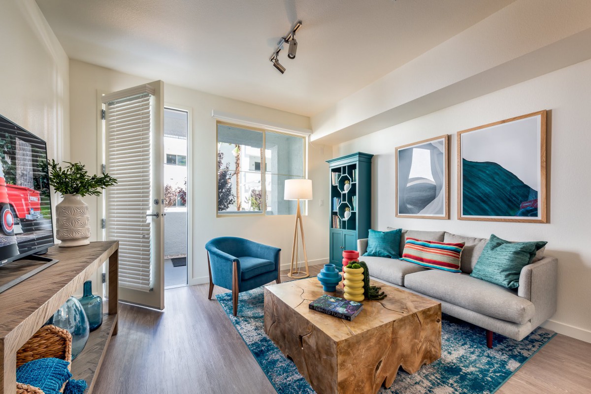 A modern and cozy living room with blue accents, featuring a wooden coffee table and ample natural light.