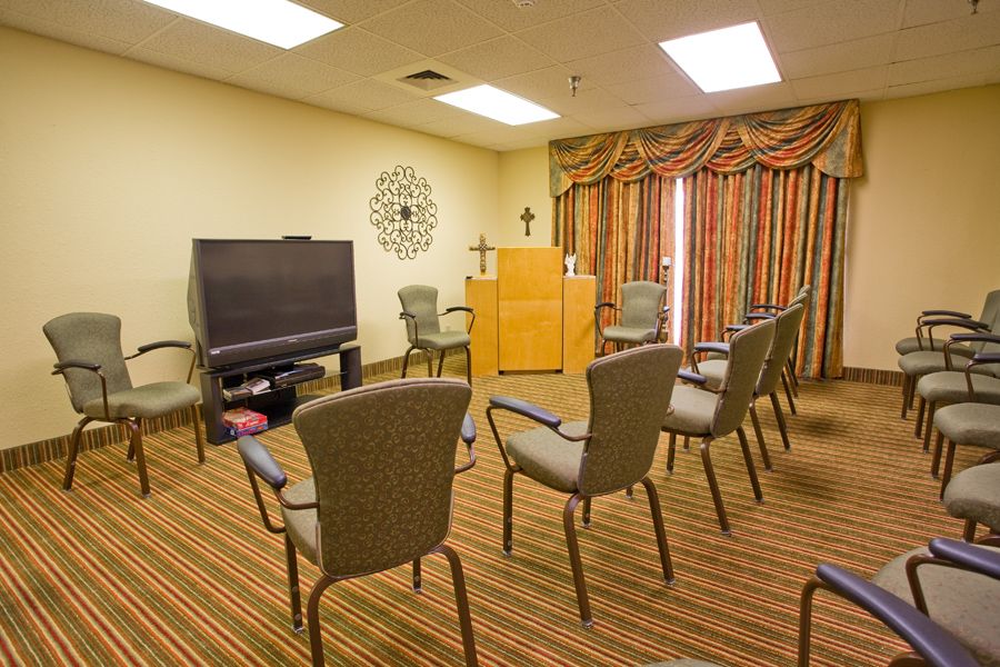 A meeting room setup with chairs arranged in a circle, a television, and a podium at the front.