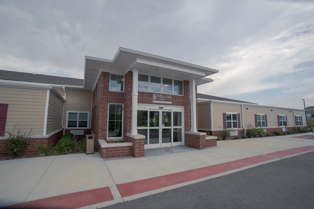 A modern school building with a brick facade and prominent entrance under a cloudy sky.