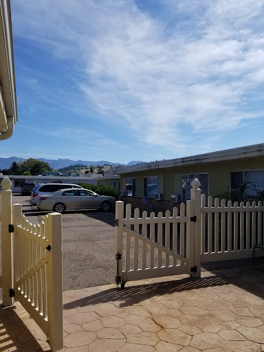 A view of a parking area surrounded by buildings and a mountain backdrop under a clear blue sky.