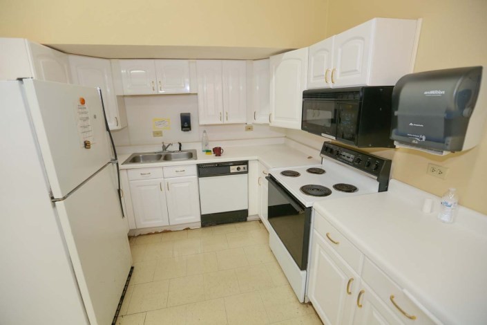 A compact kitchen with white cabinets and various appliances.